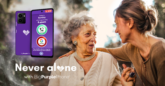Older lady and young woman smiling at each other with a BigPurplePhone next to them. The text reads 'never alone with big purple phone'.