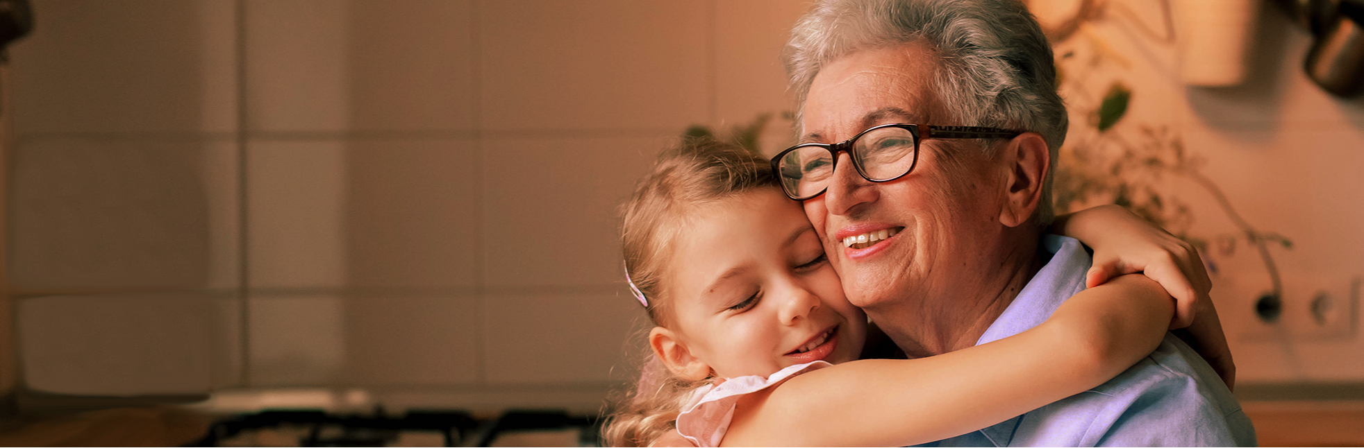 Grandparent and granddaughter hugging in a kitchen with a image of BigPurplePhone No 1 seniors phone 'Never Alone' logo.